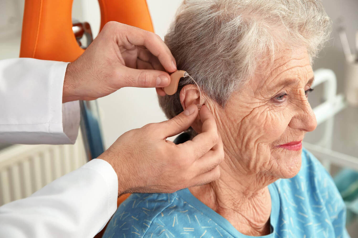 lekarz zakłada seniorce darmowy aparat słuchowy dla seniora